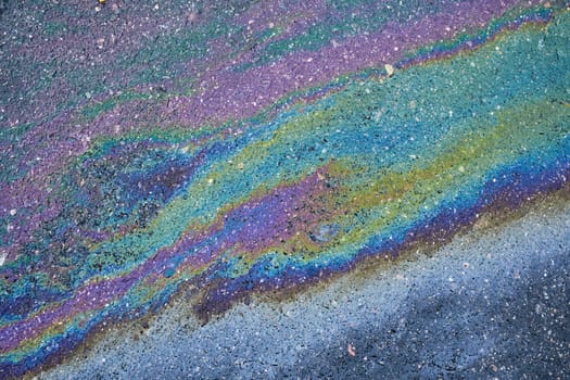 A rainbow oil spill on an asphalt road creating an abstract, surreal backdrop