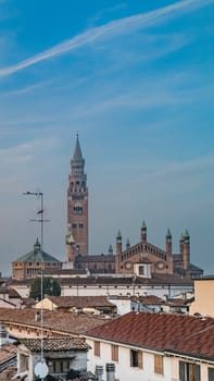 Cremona duomo cathedral towers over the city, blending with rooftops and buildings against blue sky aerial shot