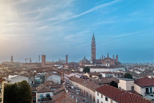 The charming city of cremona in italy at sunset, showcasing rooftops, the duomo, and the torrazzo bell tower, blending historic architecture with terracotta roofs in a picturesque scene