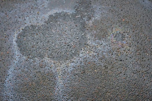 Automotive fluid leaking onto asphalt. Oil residue on asphalt surface.