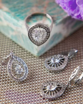 Silver jewelry set with large stones is lying on a table with a turquoise casket and a purple flower