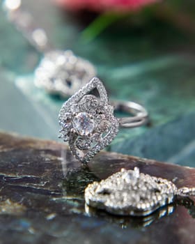 Beautiful silver ring with floral design and sparkling diamonds, placed on a stone surface