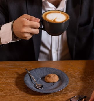 Businessman holding a cup of cappuccino with latte art enjoying a coffee break