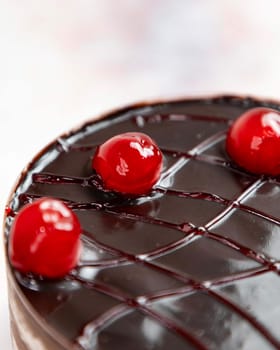 Chocolate cake with a shiny chocolate glaze and cherries on top, showing the concept of celebrating with delicious desserts