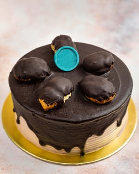 Delicious chocolate cake decorated with chocolate topping and small chocolate cakes on a golden plate