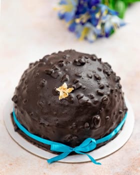 Chocolate bomb cake with a blue ribbon decorated with a gold leaf on a marble table