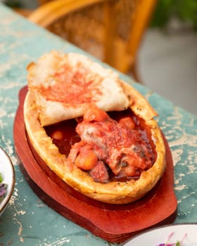 Enjoying traditional tajik cuisine with meat and tomatoes in rich sauce, covered with flatbread