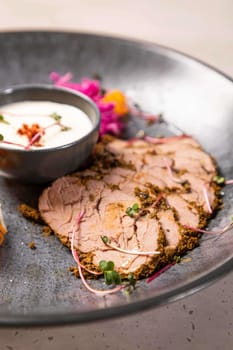 Slices of roast beef tenderloin seasoned with spices and herbs are served on a plate with sauce