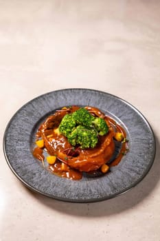 Salmon steak with vegetables and sauce, served on ceramic plate on light background