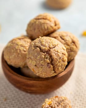 Oatmeal raisin cookies stacked in wooden bowl, sitting on white cloth