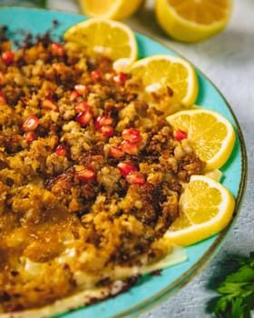 Spicy minced lamb dish garnished with pomegranate seeds and lemon slices, showcasing middle eastern cuisine