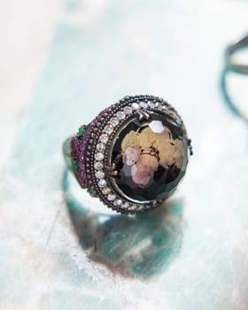 Beautiful silver ring with a large dark gem and small emeralds and rubies as decoration