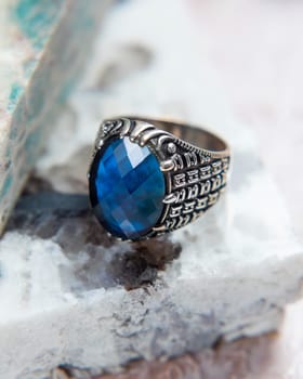 Silver men's ring with blue gem on white marble background