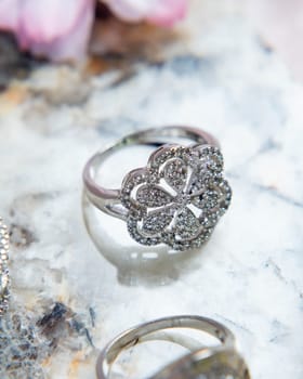 Silver ring with floral ornament encrusted with small diamonds on light background