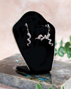 Silver ring and earrings with a unique wave design are displayed on a black jewelry display, showcasing the sparkle of the diamonds