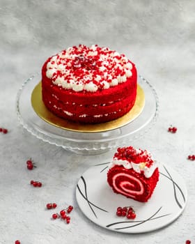 Delicious red velvet roll cake and layered cake decorated with redcurrants, white cream and crumbs on a white background