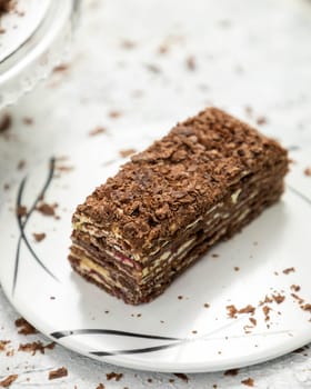Delicious chocolate cake layered with chocolate shavings on white plate