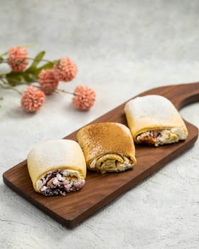 Three delicious sweet buns with different fillings lying on wooden board