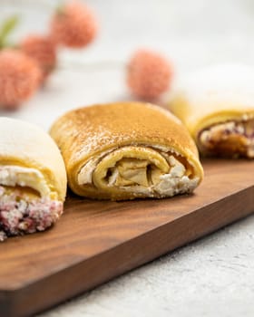 Three appetizing sweet rolls with various fillings are lying on a wooden board