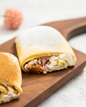 Freshly baked meringue roll with raspberries and whipped cream filling sprinkled with powdered sugar