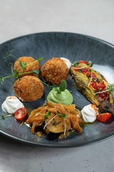 Delicious vegan appetizer platter is being served on a gray plate at a restaurant