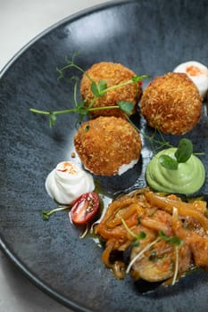 Arancini rice balls served with dipping sauces are garnished with fresh herbs for a touch of elegance