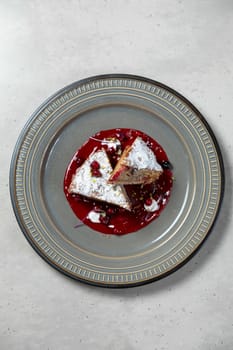Two slices of delicious cake with berry sauce are sitting on a modern plate