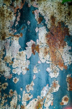 An abstract depiction macro of rusted metal featuring peeling paint with vibrant colors. Highlights complex textures and weathered surfaces, conveying a sense of decay and artistic expression