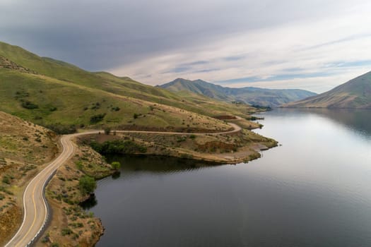 A road with a lake in the background. The road is winding and the sky is cloudy