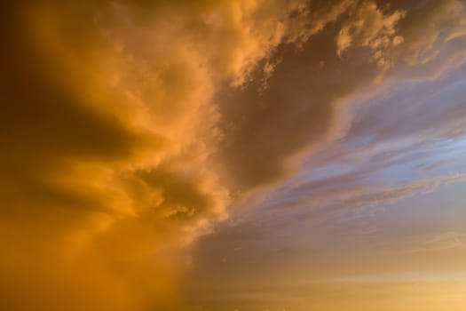 The sky is orange and cloudy. The clouds are low and the sun is setting. The sky is a mix of orange and blue
