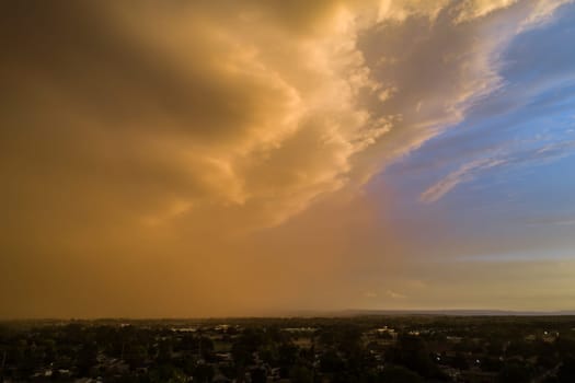 A cloudy sky with a bright orange sun in the background. The sky is hazy and the sun is setting