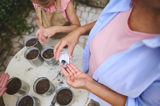 Family bonding over a gardening activity, planting seeds in recycled containers outdoors. The image captures hands-on teamwork and shared environmental responsibility in a cozy garden setting.