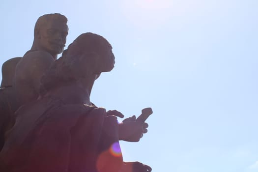 A striking statue depicts a man and woman, highlighting their details against a bright midday sky, symbolizing connection and creativity.