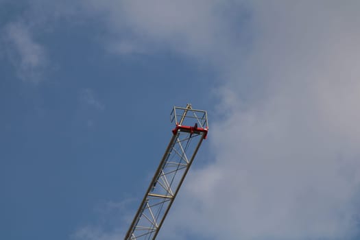 A construction crane towers high above the city, its metal frame standing out against the blue sky. Workers can be seen safely operating from the top, contributing to urban growth.