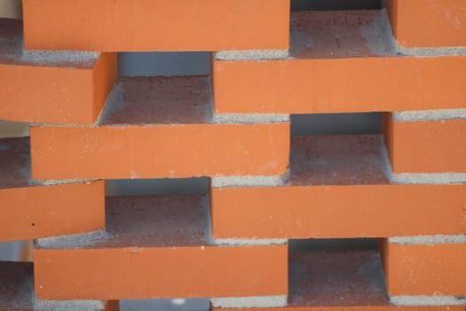 Interlocking orange bricks are neatly stacked in a precise arrangement, showcasing their textured surfaces and mortar lines, ideal for building projects.