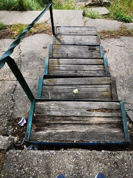 Weathered wooden steps descend into a neglected backyard filled with overgrown grass and scattered debris, illustrating the passage of time and nature's encroachment.