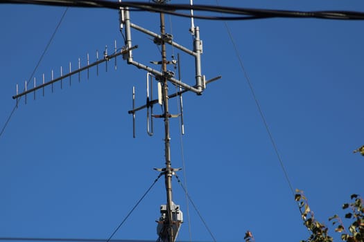 Tall communication tower equipped with multiple antennas reaches towards a bright blue sky, emphasizing its role in urban connectivity and telecommunications.