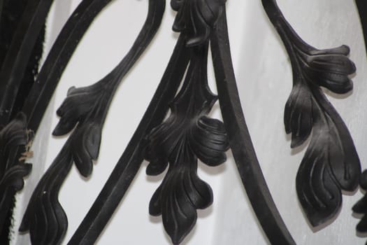 Intricate floral patterns in black metal are showcased against a white background, highlighting craftsmanship and design details in the bright light.