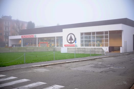 Cremona, Lombardy, Italy - November 7th 2024 Eurospar supermarket building shrouded in fog, showcasing its logo and parking area on a quiet day