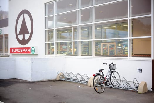 Cremona, Lombardy, Italy - November 7th 2024 Bicycle parked near empty bike rack in front of eurospar supermarket