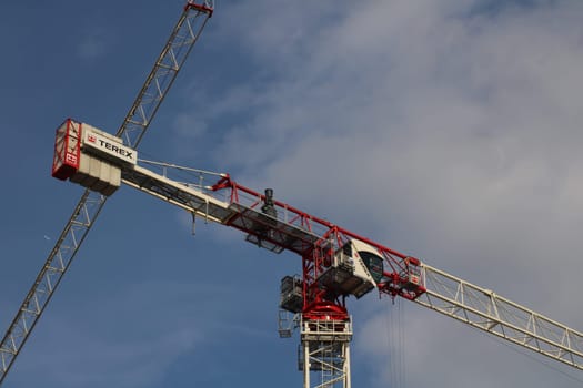 A large construction crane stands tall against a blue sky, actively used in the development of urban infrastructure, highlighting ongoing construction efforts.