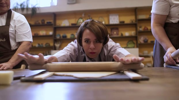 A determined and passionate baker diligently practices rolling dough in a lively and engaging cooking class environment. Stock Clip