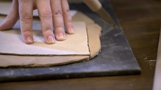 A skilled craftsman shapes soft clay on a smooth surface, showcasing intricate pottery techniques and artistry. Stock Clip