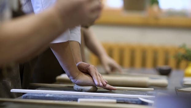 In a pottery class, participants are enthusiastically shaping clay, showcasing their creativity and craftsmanship. Stock Clip