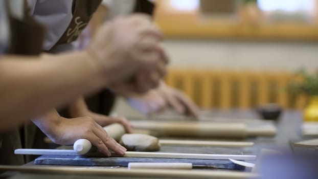 In a pottery class, participants are enthusiastically shaping clay, showcasing their creativity and craftsmanship. Stock Clip