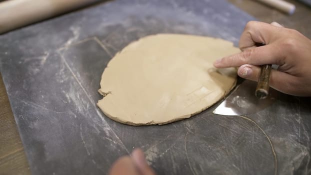 Skilled hands shape soft clay into art using tools in a workspace, showcasing unique pottery techniques. Stock Clip