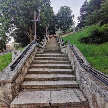 A well-maintained stairway made of stone ascends through a quiet park. Flanked by vibrant greenery, it invites visitors for a peaceful stroll while surrounded by nature.