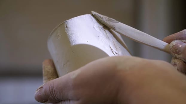 A detailed close up of hands meticulously smoothing and shaping clay on a pottery piece using a spatula. Stock Clip