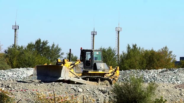 A bulldozer is actively working on a construction site where communication towers can be seen in the background. Stock Clip