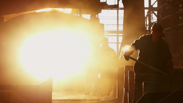 A silhouette of a dedicated worker stands out against a bright, industrial background filled with dust. Stock Clip